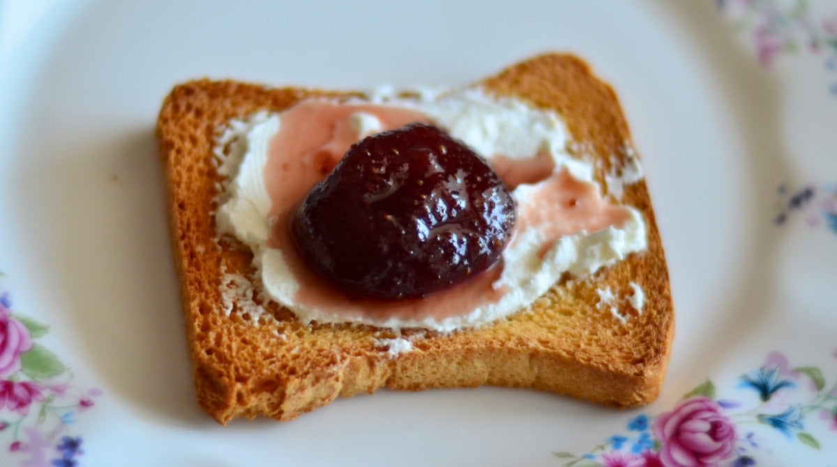 Kahvaltılık tost dilimi üzerinde krem peynir ve çilek reçeli